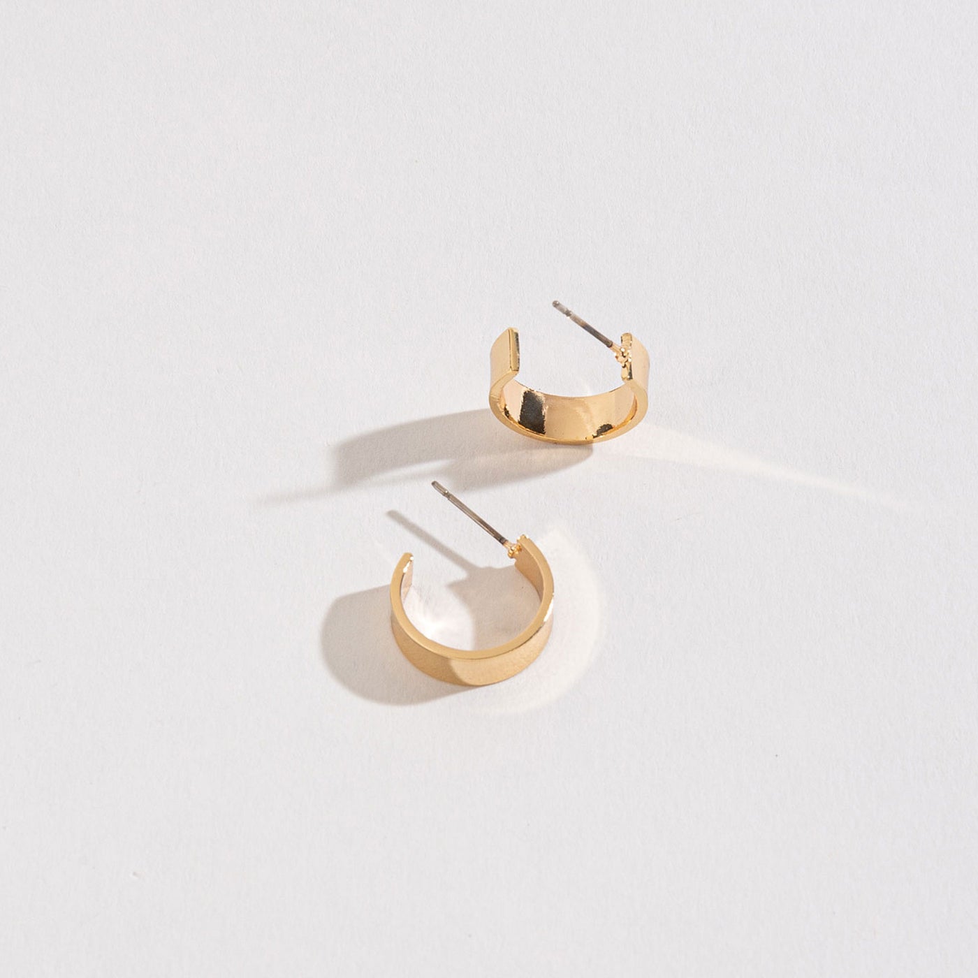 gold flat huggie hoops on a white background.