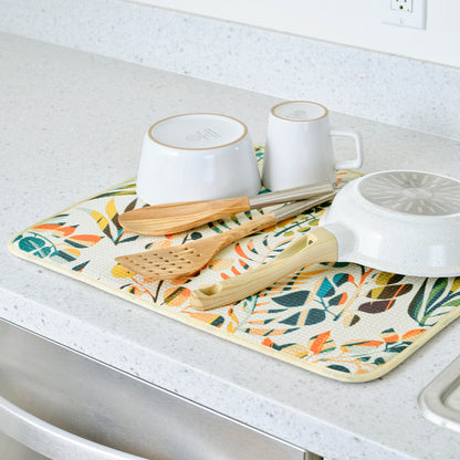 cream dish drying mat with colorful leaf design on a kitchen counter with dishes on it