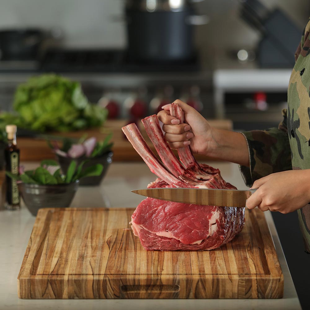 side view of carving board on a kitchen counter with a slab of meat being cut on it.