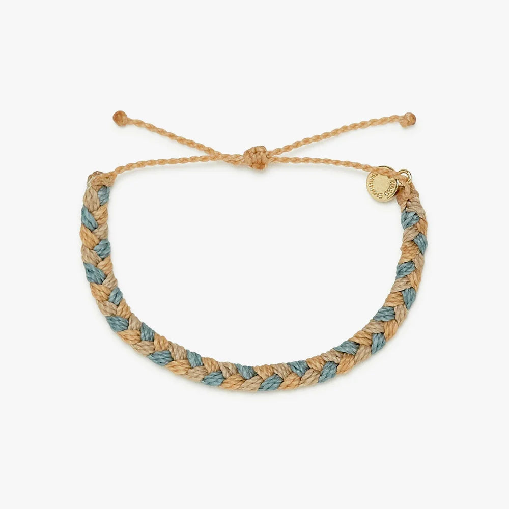 Pura Vida braided bracelet with varying shades of tan and blue with a Pura Vida charm