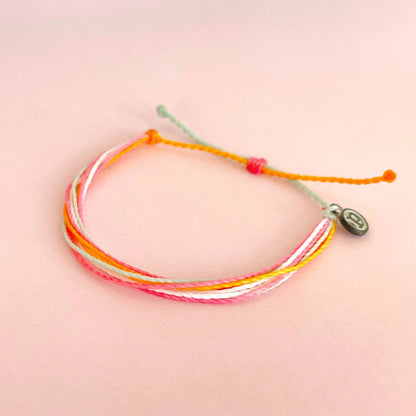 Pura Vida multi strand corded bracelet in varying shades of pink, white, and orange with a Pura Vida logo charm