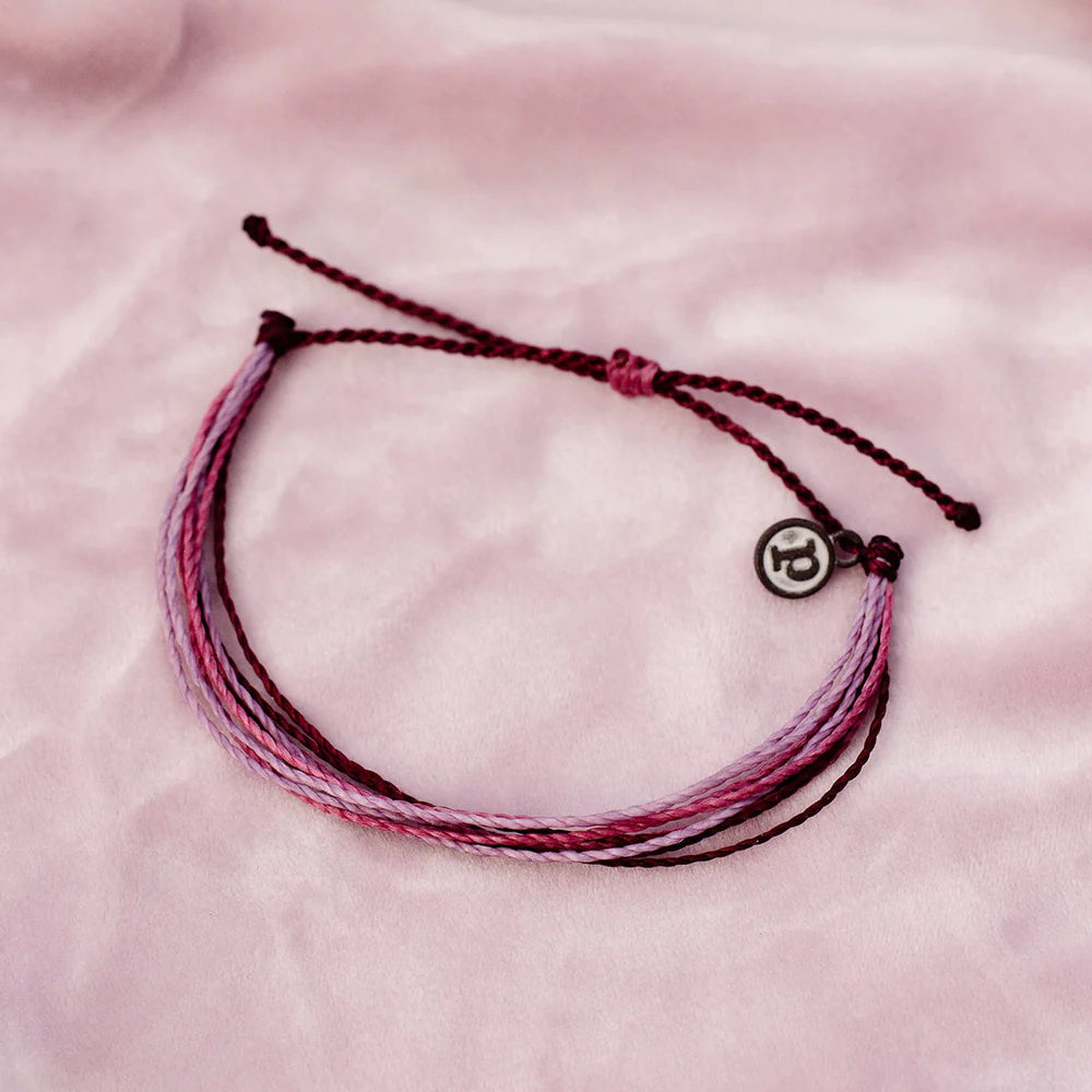 Pura Vida multi strand corded bracelet in varying shades of purple and pink with a Pura Vida logo charm