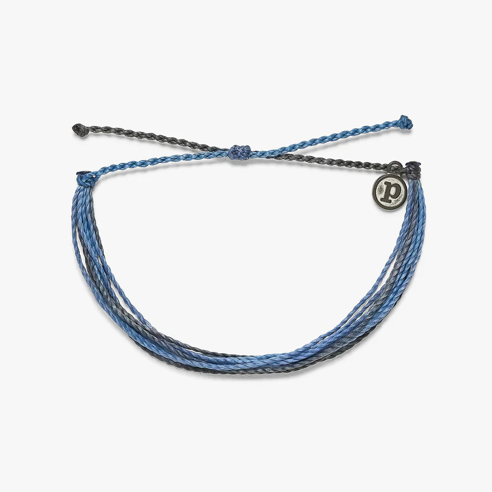 Pura Vida multi strand corded bracelet in varying shades of blue and gray with a Pura Vida logo charm