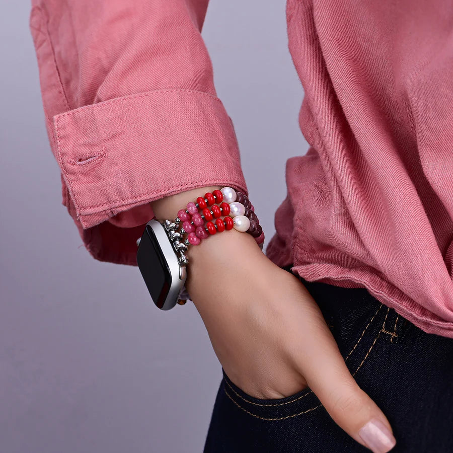 Person wearing a smartwatch with beaded strap in pinks, white, and pear