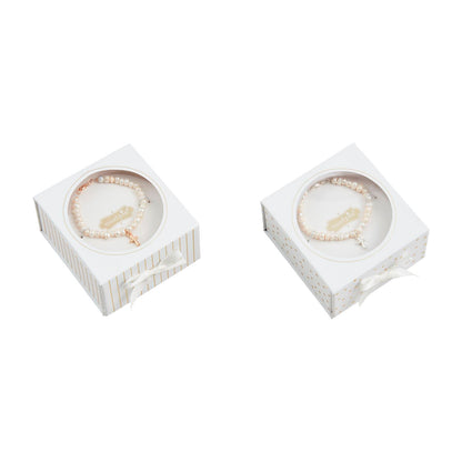 Two white gift boxes with cross bracelets inside