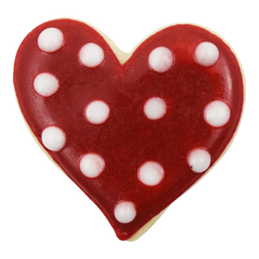 Heart-shaped cookie with red icing and white polka dots on a white background