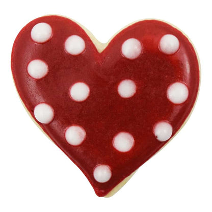 Heart-shaped cookie with red icing and white polka dots on a white background