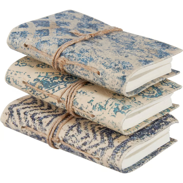 Stack of three patterned mini notebooks tied with string on a white background