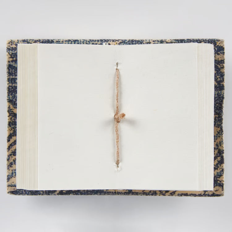 Open mini note book with jute binding on a light gray background