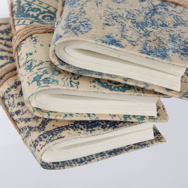 close-up of Stack of notebooks with textured blue and beige cover on a white background