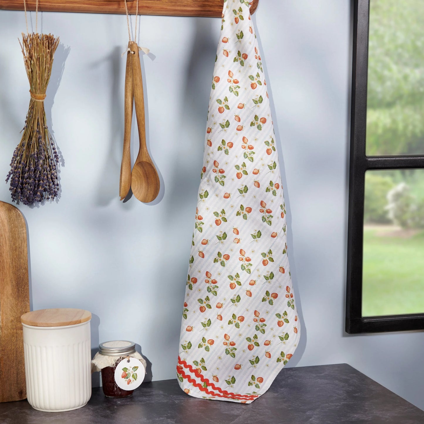strawberry-patterned towel hanging on a wooden rack with kitchen items in the background.