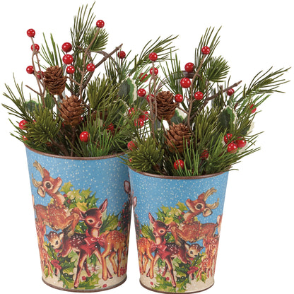 2 sizes of metal buckets with deer designs filled with evergreen sprigs, red berries, and pinecones