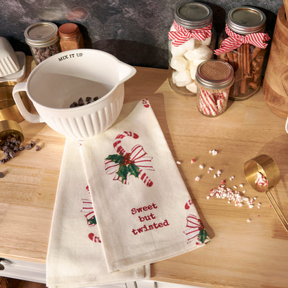 sweet but twisted towel draped on a counter with a mixing bowl and ingredients arranged around it.