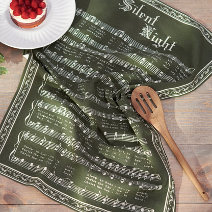 silent night towel draped on a countertop with a wooden spoon and a fruit dessert.