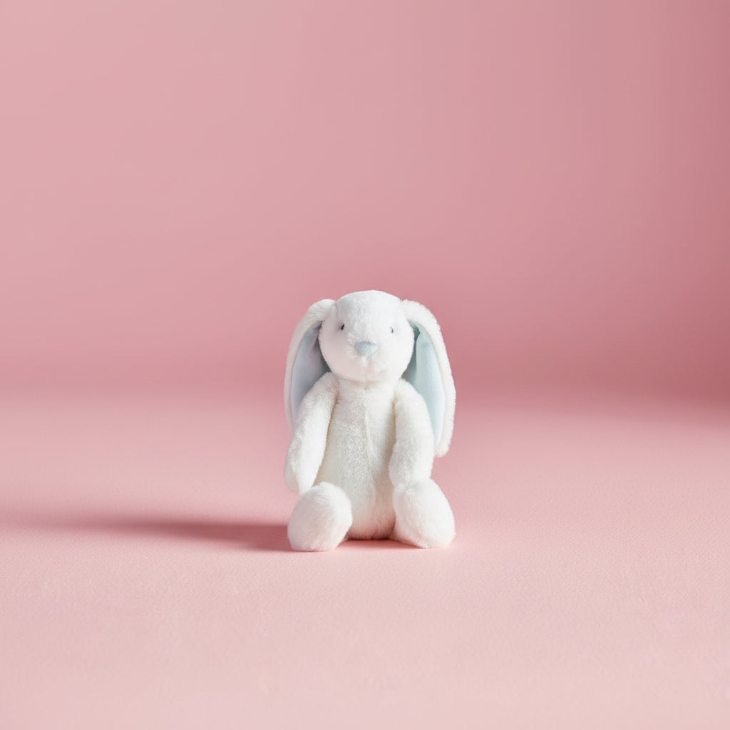 white bunny with blue interior ears seated on a pink bakground