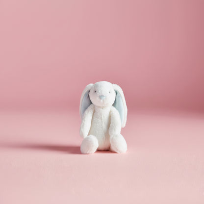 white bunny with blue interior ears seated on a pink bakground