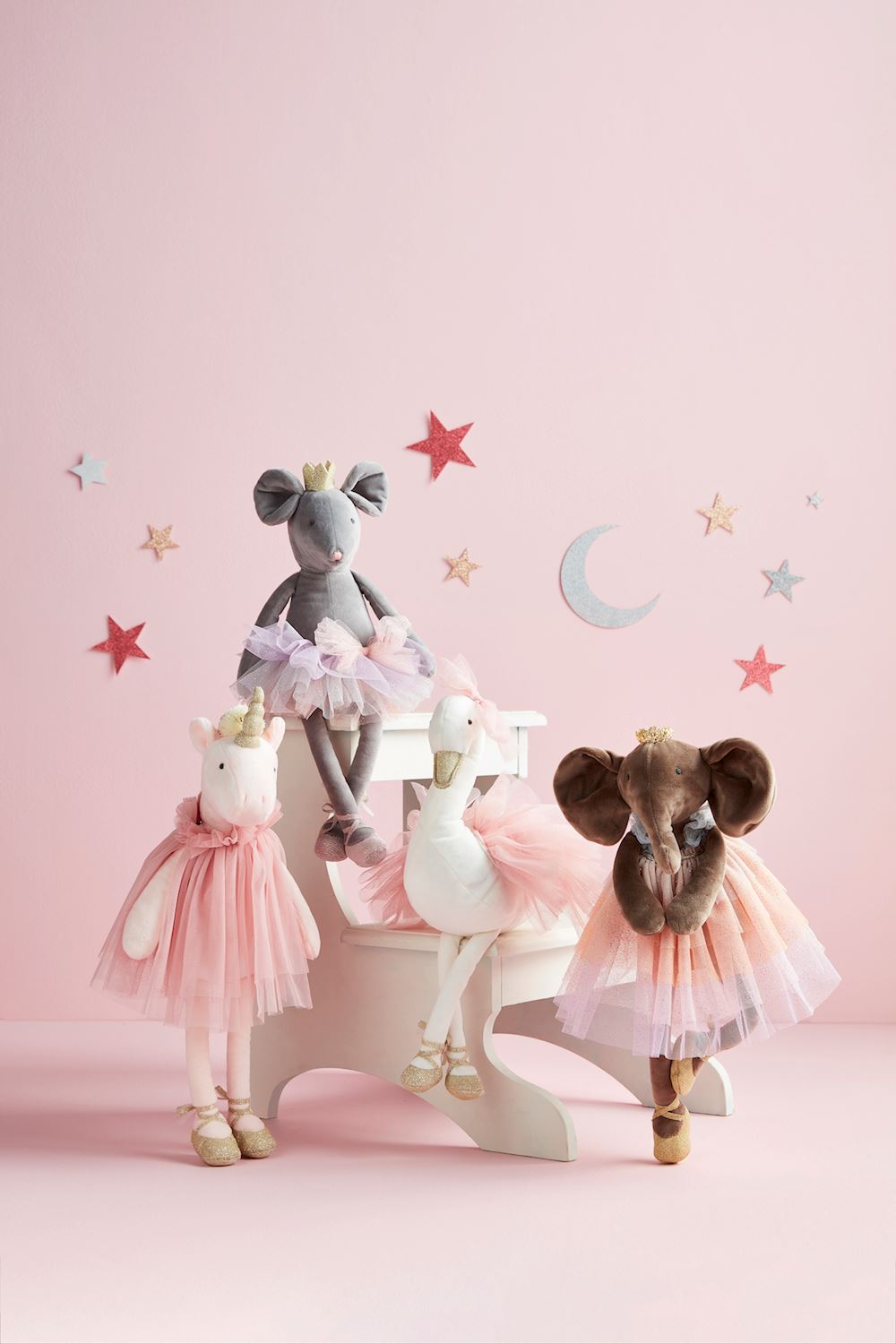 four plush princess toys on a pink background