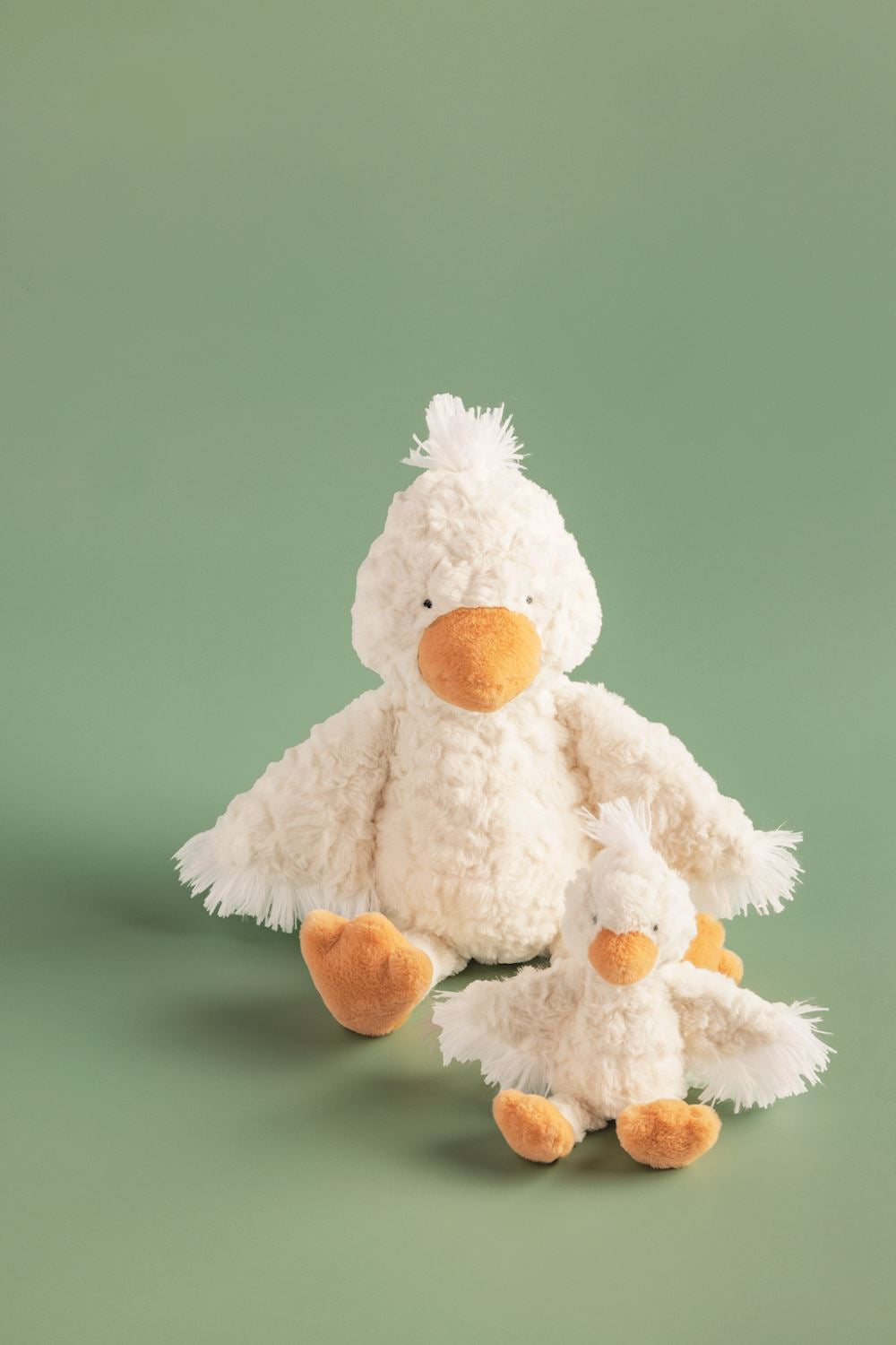 large and small plush duck toys on a green background