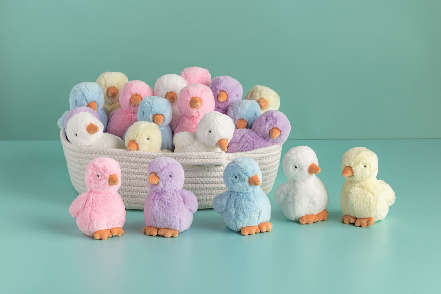 Pastel-colored plush chicks in a basket on a light blue background