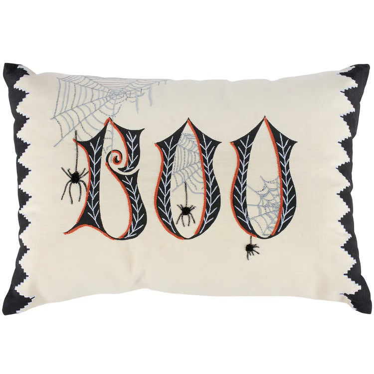 A Halloween throw pillow with a cream background, featuring the word 'BOO' in large black gothic letters with spider and cobweb details, and a black zigzag border.