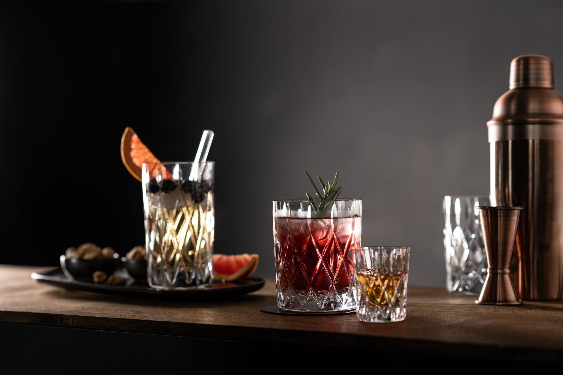 assortment of cut glass drinking glasses filled with beverages arranged on a wooden surface