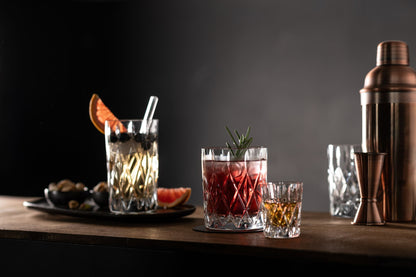 assortment of cut glass drinking glasses filled with beverages arranged on a wooden surface