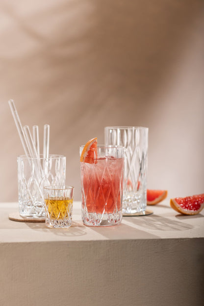 assorted glass drinking glasses arranged on a table, 2 glasses are filled with beverages