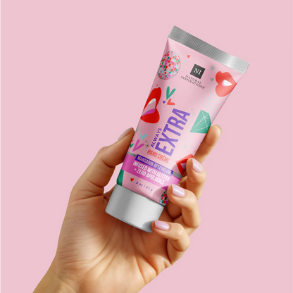 Hand holding a tube of 'Always Extra' hand cream against a pink background