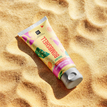 Tube of bombshell hand hand cream laying on sand