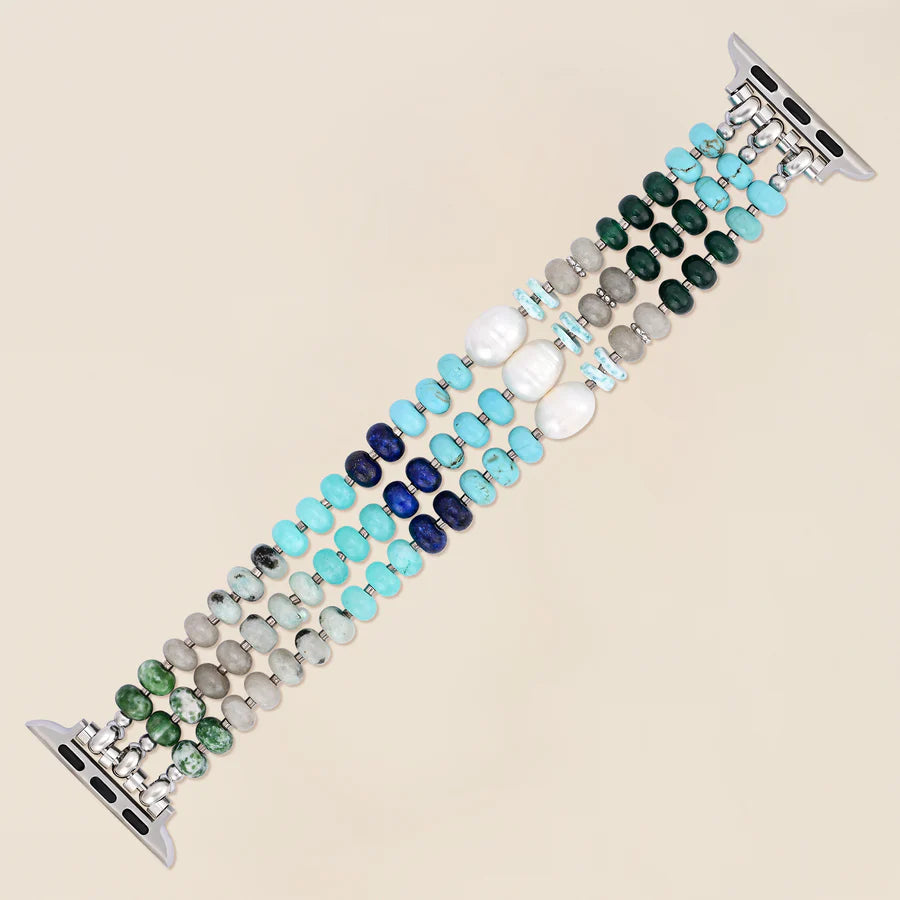 blue, green, and pearl beaded watch band laying flat on a beige background