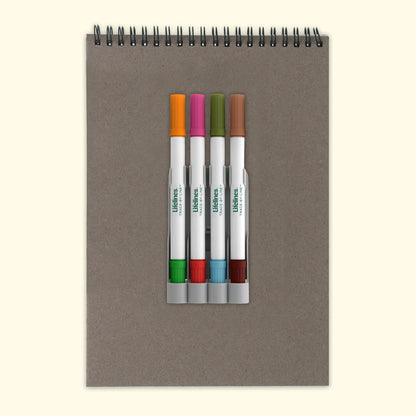 Notebook with a set of white markers on a beige background