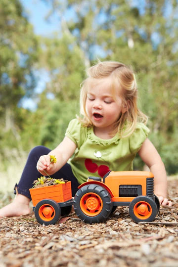 small child playing with tractor in a garden.