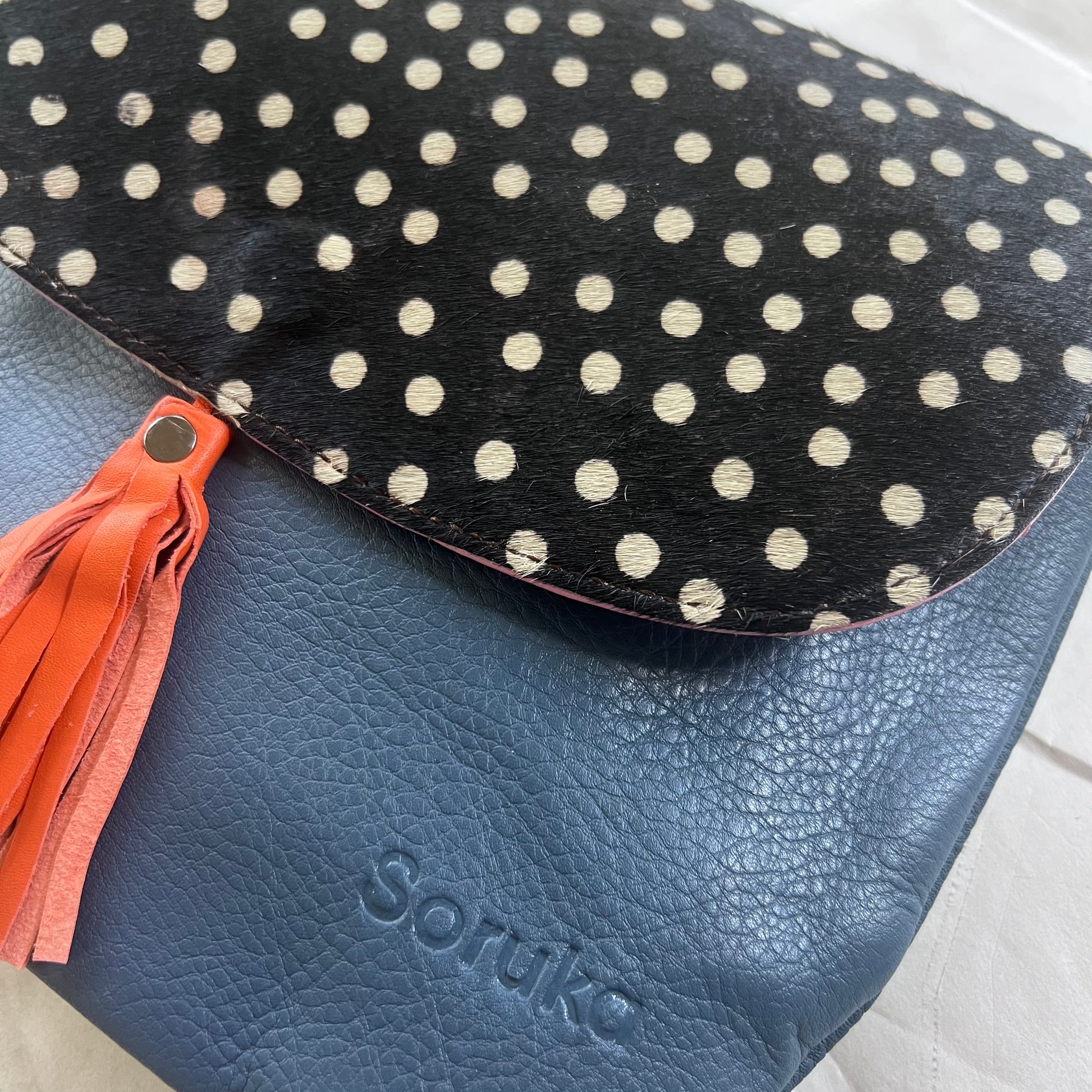 close-up of orange tassel Lola Reversible Crossbody