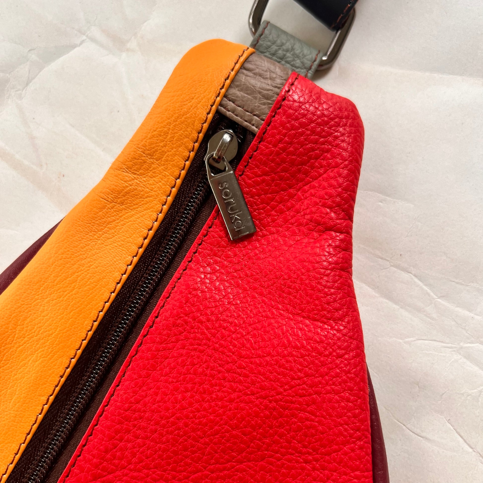 close-up of top of roxi sling bag showing zipper pull.