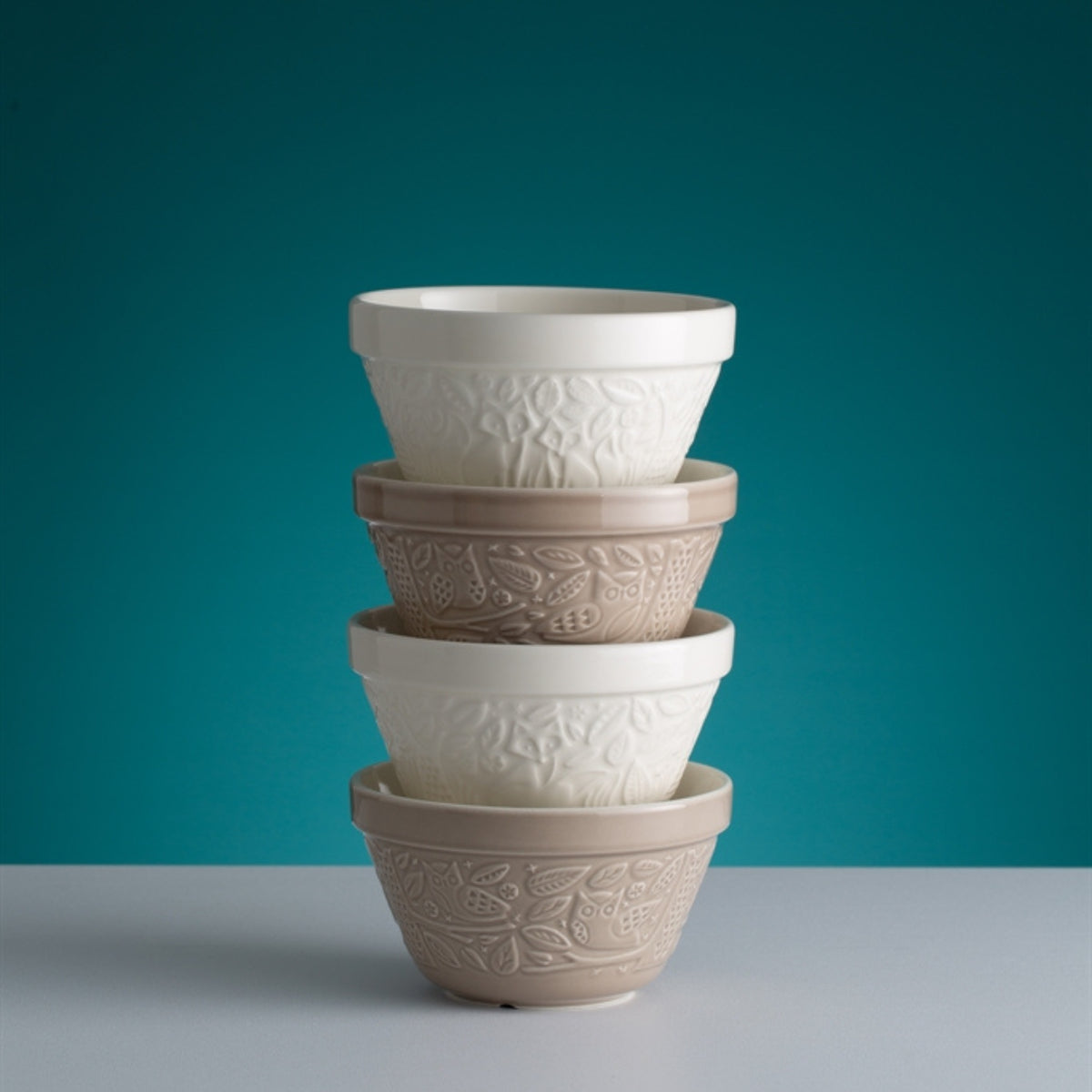 Stack of ceramic bowls with textured design against a teal background