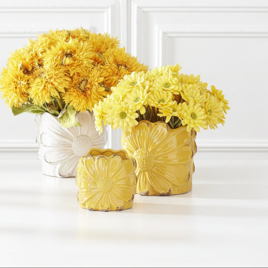 2 different sized yellow flower pots with large sunflowers embossed on them, the larger pot in filled with yellow daisies