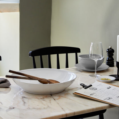 Friso Shallow Serving Bowl with wooden serving utensils in it set on a table