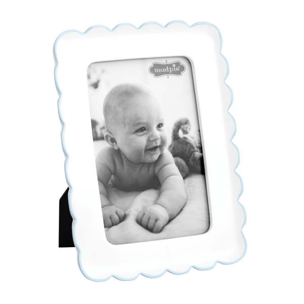 White scalloped photo frame with thin blue trim and a black and white photo of a baby on a white background