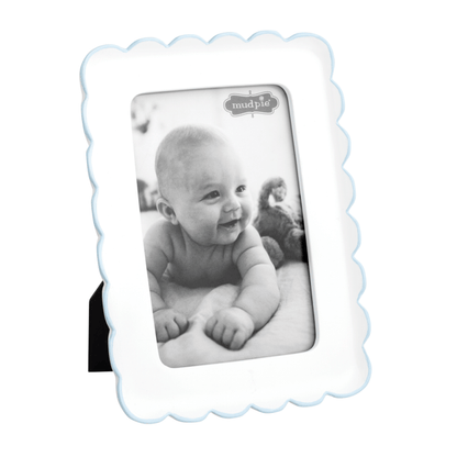 White scalloped photo frame with thin blue trim and a black and white photo of a baby on a white background