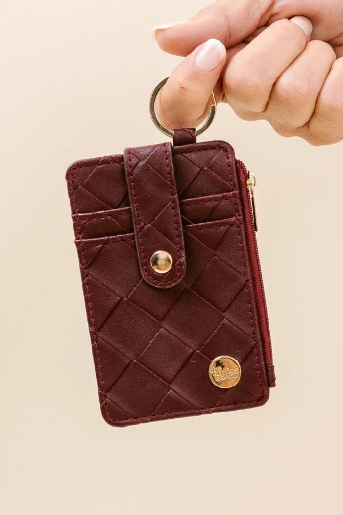 hand holding plum wallet by the keyring.