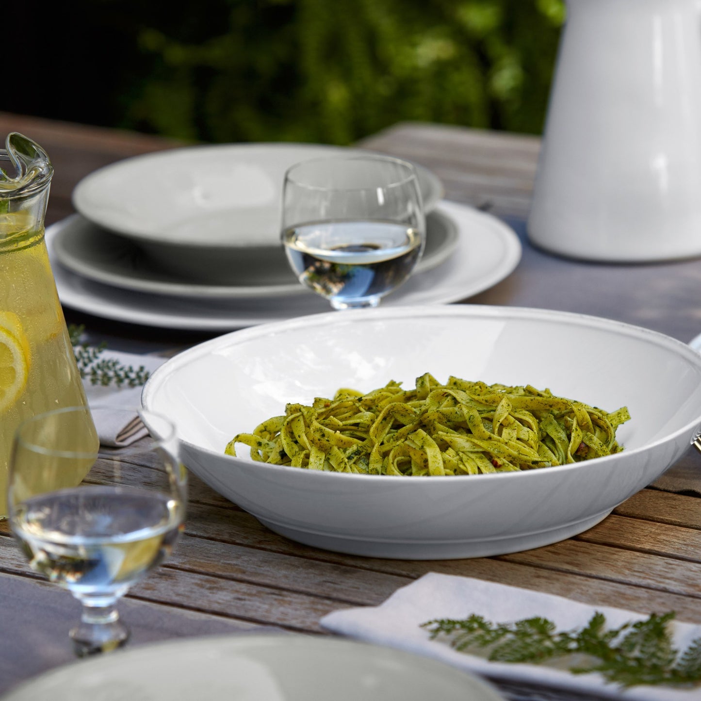 Friso Shallow Serving Bowl filled with pasta and set on a table with other dishes