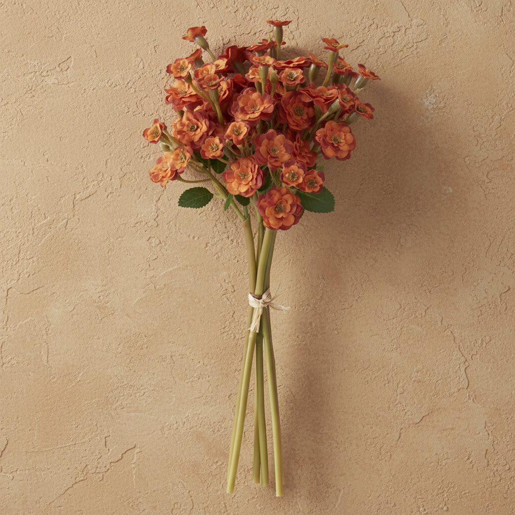 bundle of orange primrose flowers shown on a tan plaster background