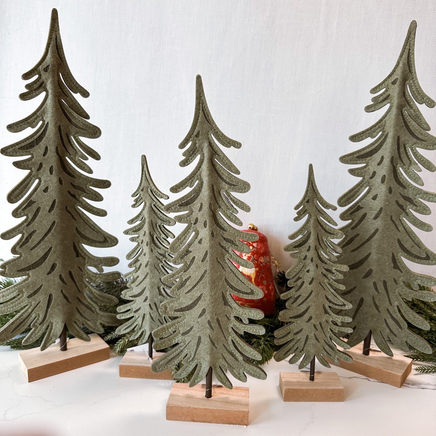 Collection of small, medium, and large felt, flat trees on a wood base.
