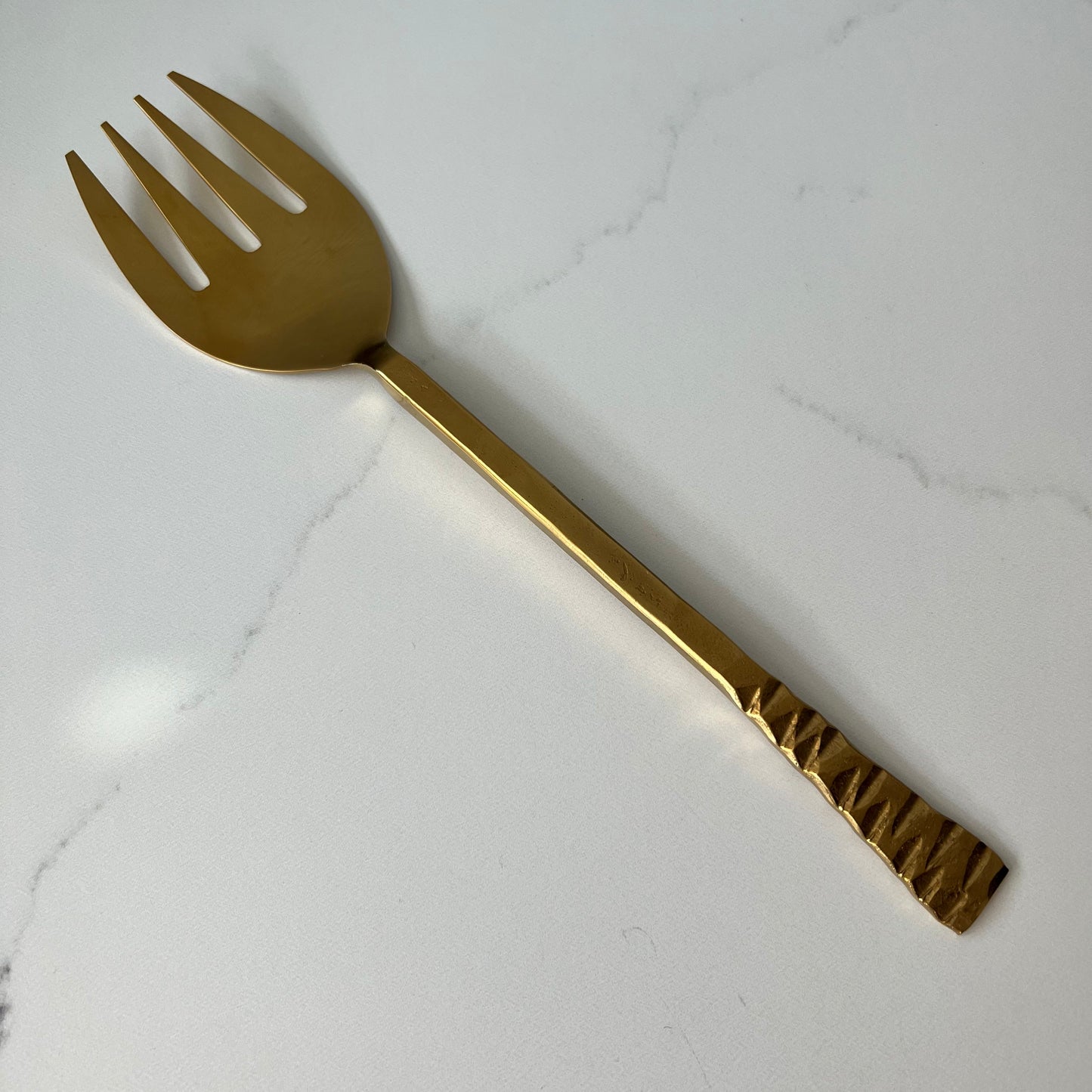 large gold fork on a marble countertop.