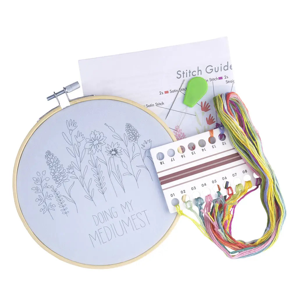 Embroidery kit with hoop, floral design, thread, and stitch guide on a white background