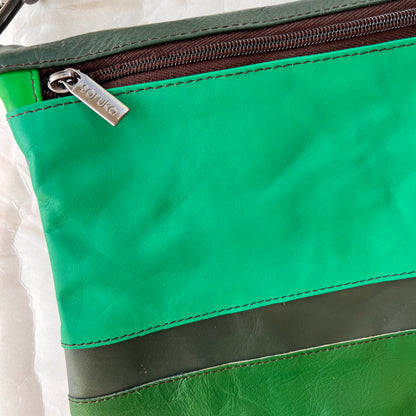 close-up of greens and grey striped greta bag with zipper across the top..