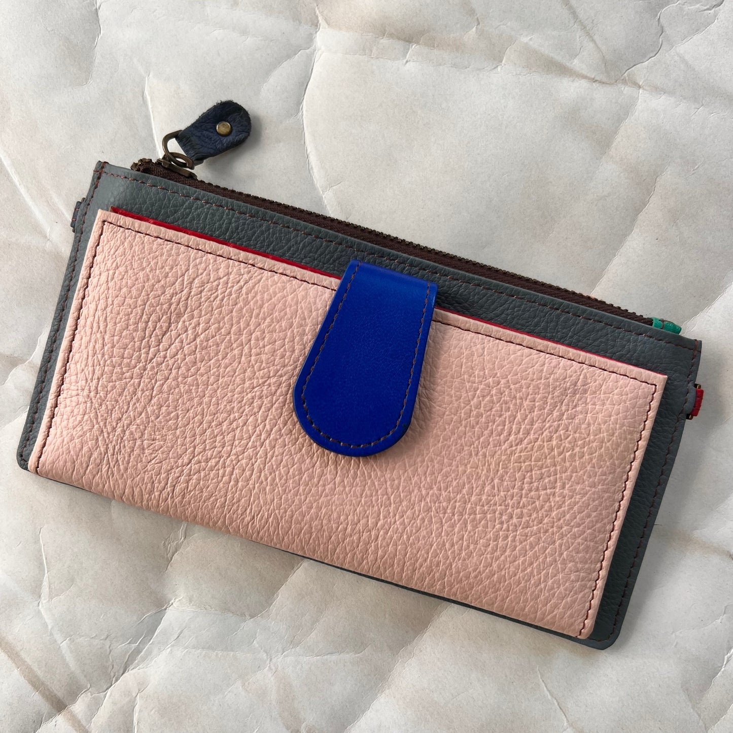 rectanglar kimber teal wallet with pink pocket and blue tab closure.