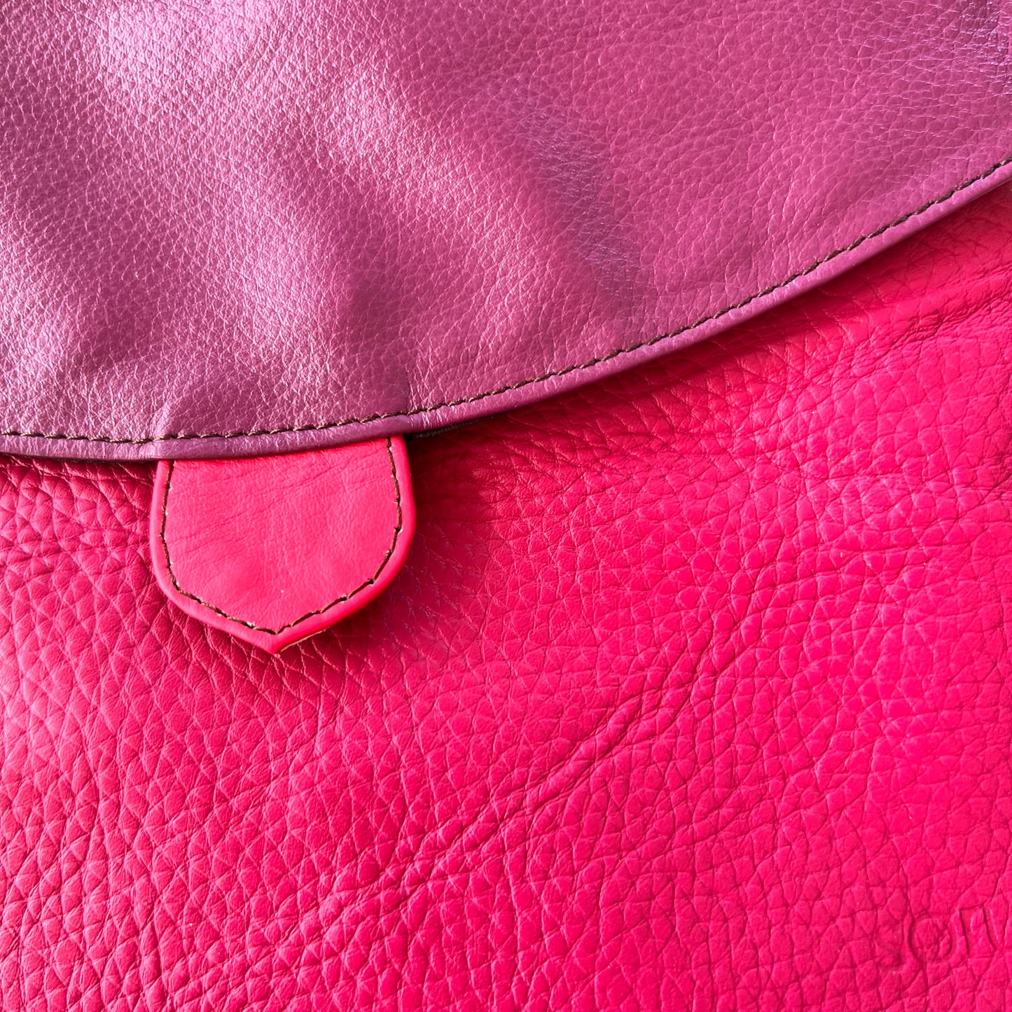 close-up of greta bag with plum flap over fuchsia body.