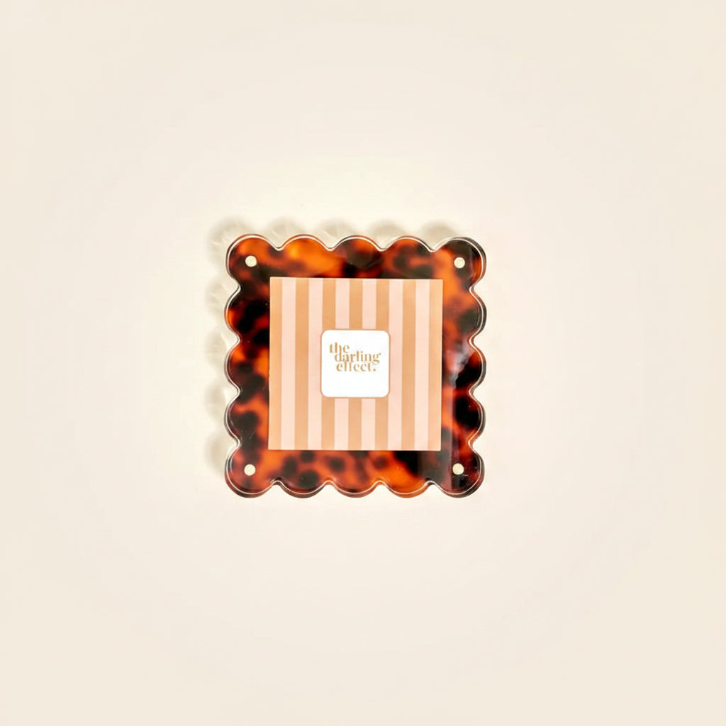 Tortoiseshell-patterned photo frame with 'the darling effect' branding inset shown on a beige background