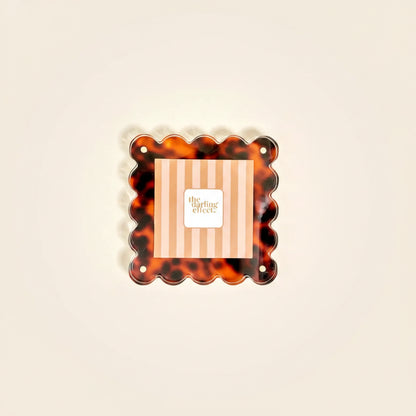 Tortoiseshell-patterned photo frame with 'the darling effect' branding inset shown on a beige background